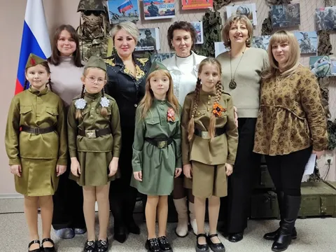 Участники в гимнастёрках с преподавателями в зале музея