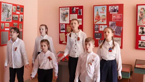 Дети с георгиевскими лентами поют у стендов выставки