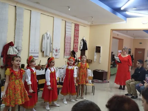 Девочки в сарафанах выступают в зале с народными костюмами и рушниками