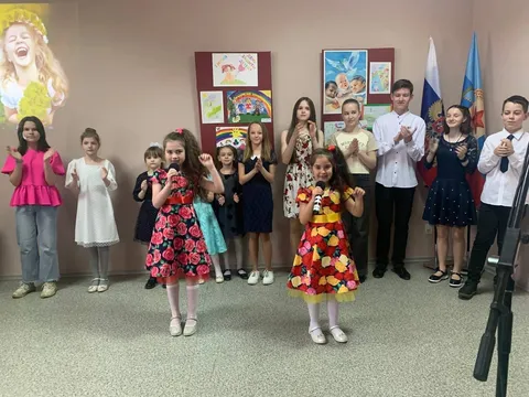 Дети поют у стенда с рисунками