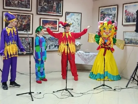 Скоморохи у микрофонов и чучело Масленицы на фоне картин