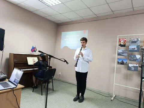 Юноша играет на кларнете у стенда с фотографиями