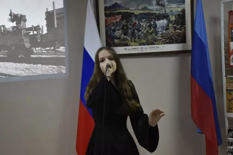 Солистка поёт, на экране — фотография военных лет