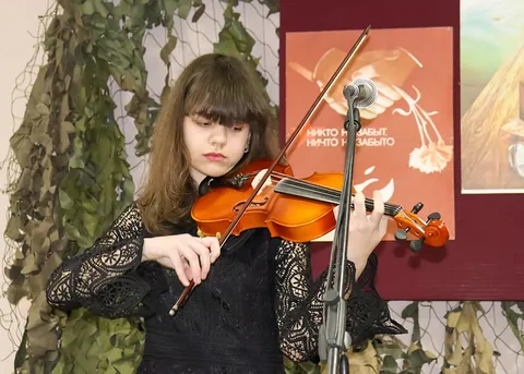 Скрипачка играет у плаката «Никто не забыт, ничто не забыто»