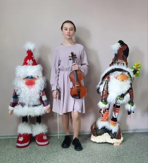 Скрипачка между фигурами Дедов Морозов