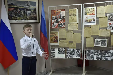 Мальчик поёт у стенда с документами