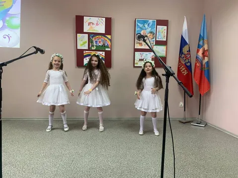 Три девочки в белых платьях поют у микрофонов